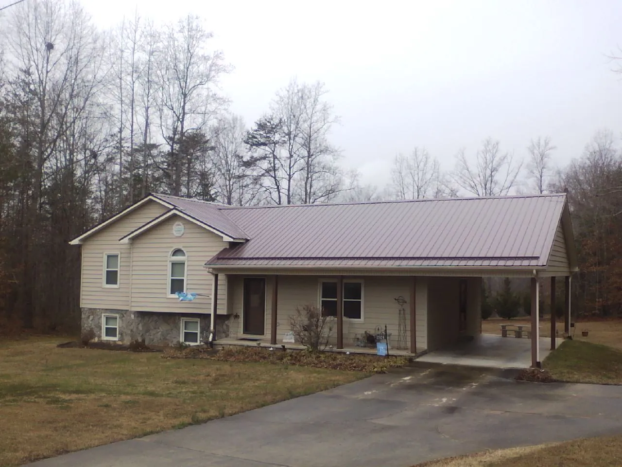 Burgundy metal roof on a tan split level home with an attached carport in Cheraw