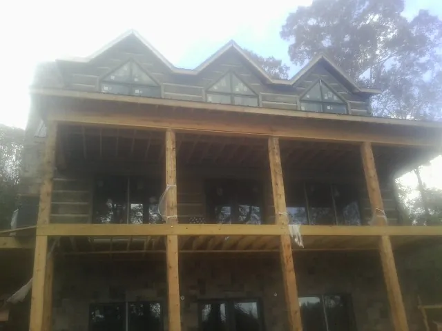 Dormers and porch framing on a large log home under construction — Roof Coating work by our crew in Cheraw
