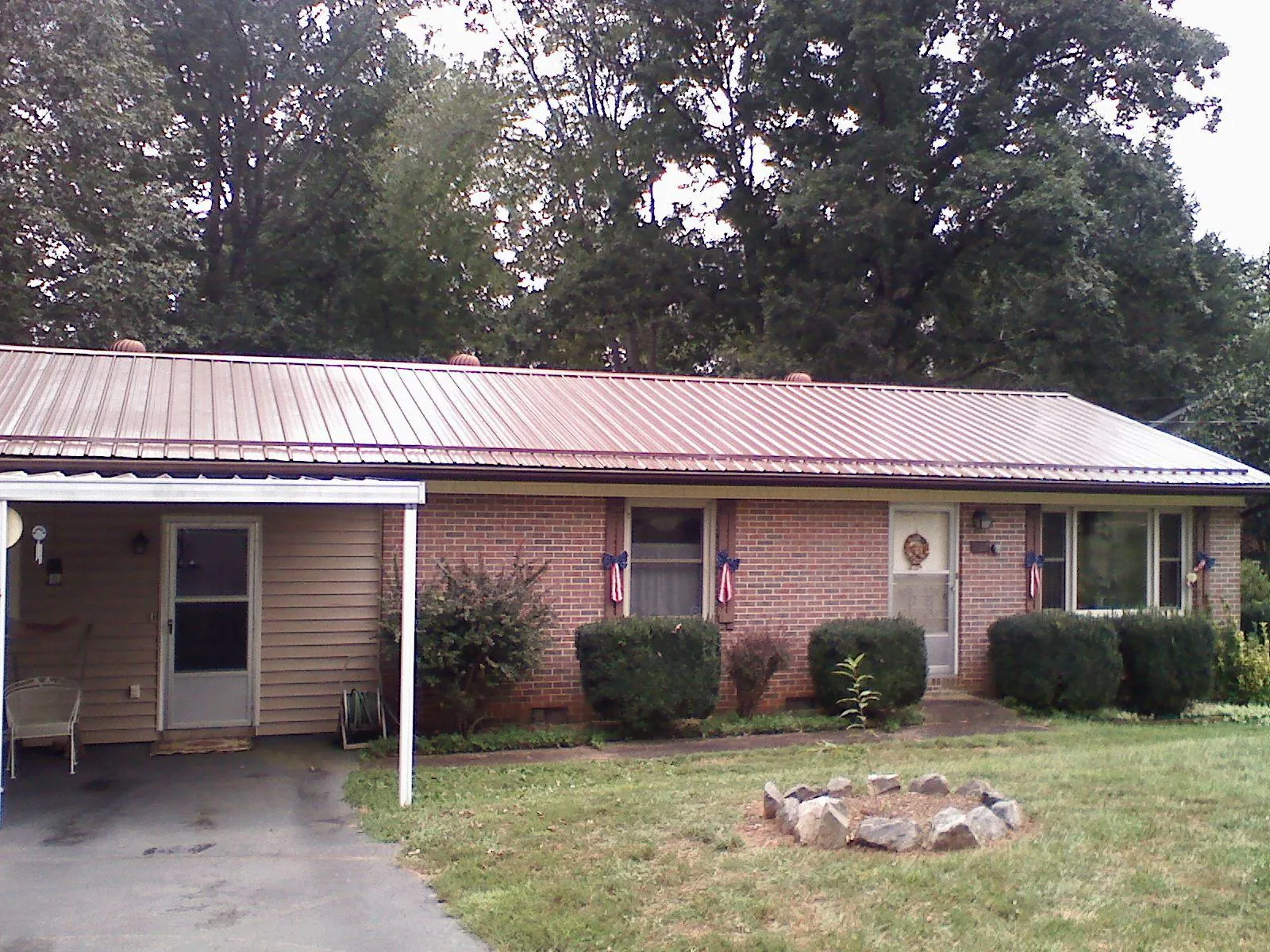 Bronze metal roof and carport on a brick ranch home — Roof Repair work by our crew in Cheraw